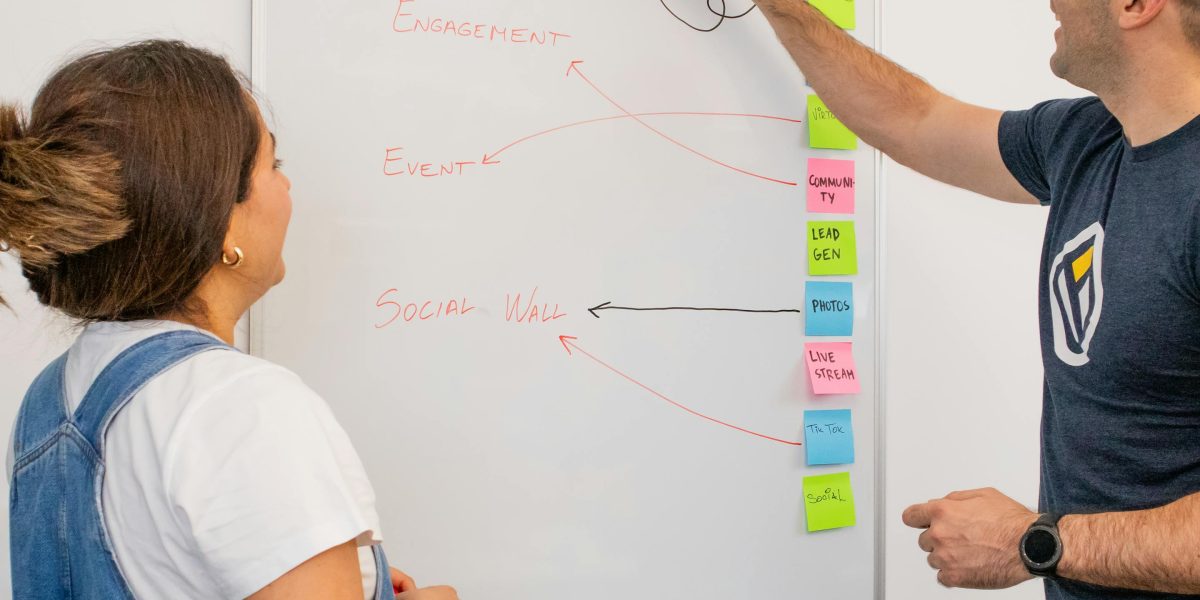 A diverse team collaborating around a whiteboard, discussing complex concepts to achieve shared understanding and avoid confusion.