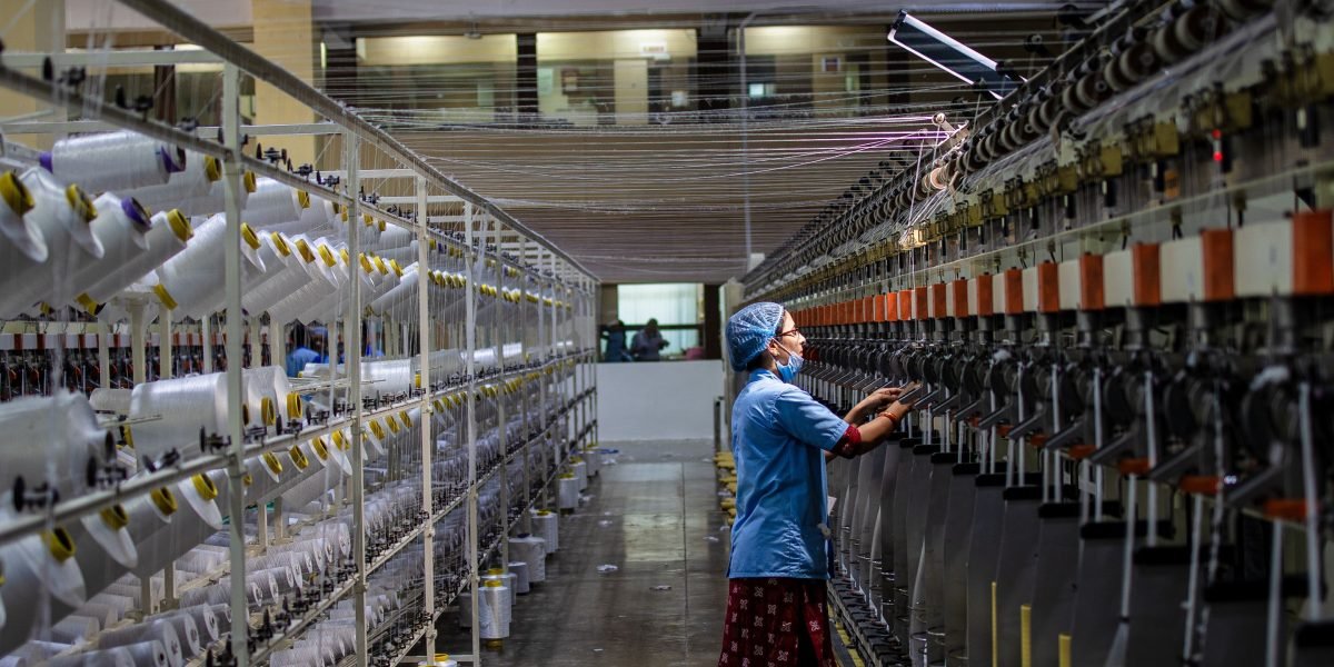 A worker in a factory setting carefully observes operations, ensuring safety amidst automated systems.