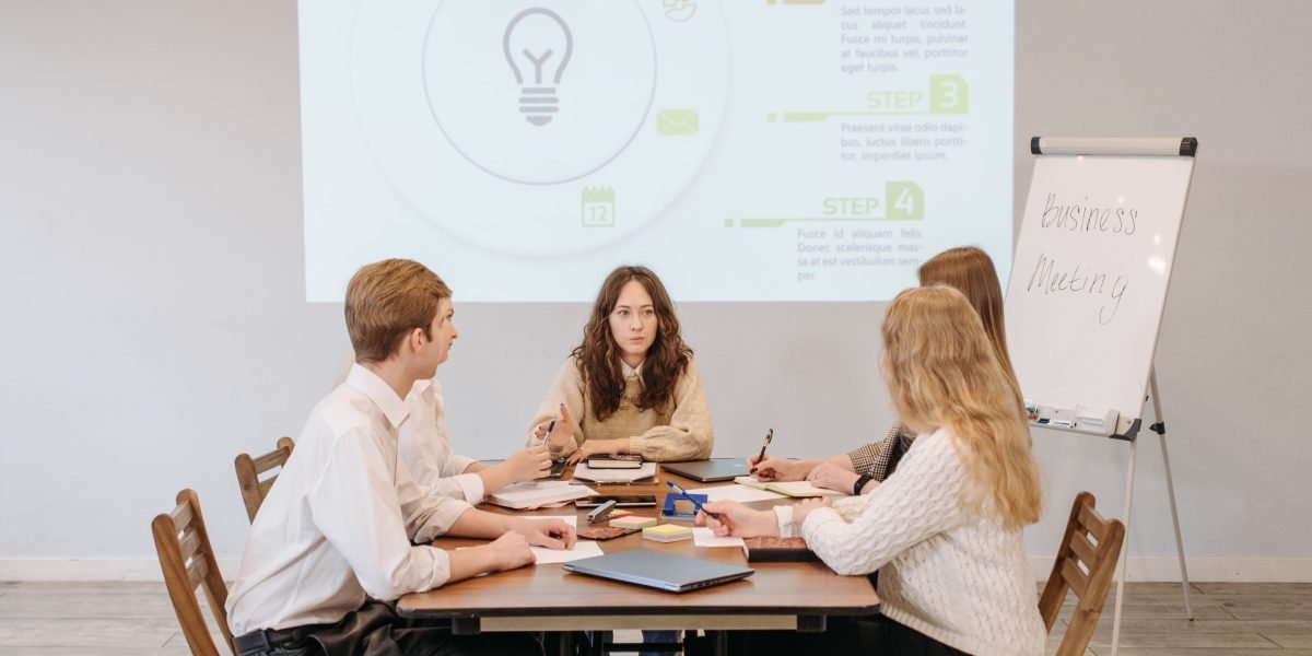 A diverse team collaborating, sharing ideas and making notes on a whiteboard during a brainstorming session.