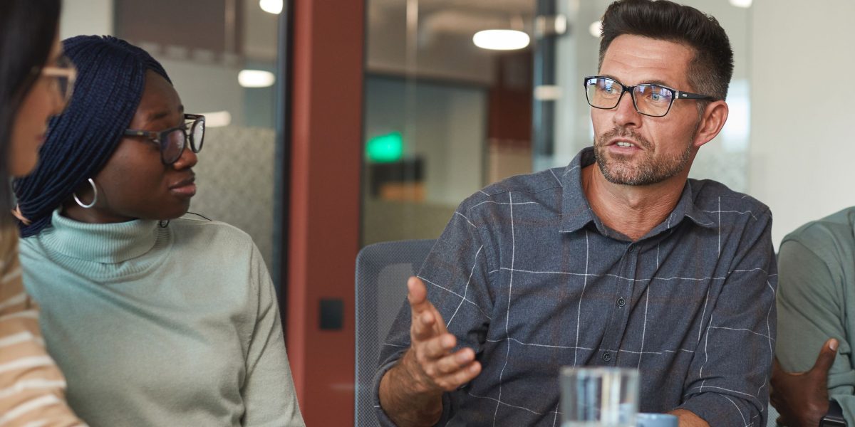 A diverse team works together in an office setting, highlighting the collaborative adoption of new technologies like AI across various industries.